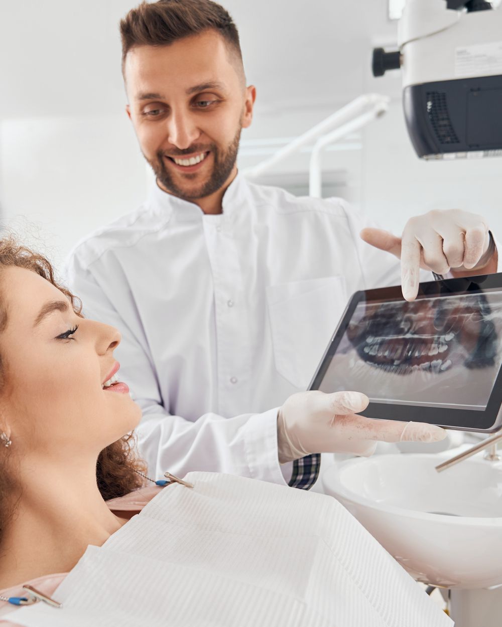 Imagem ilustrativa: dentista mostrando radiografia dos dentes em um tablet para a paciente