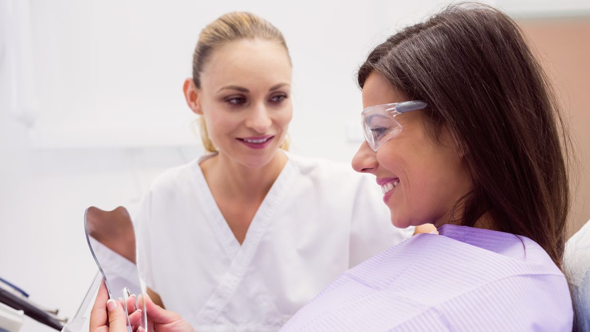 Imagem ilustrativa: paciente sorrindo diante do espelho em consultório odontológico
